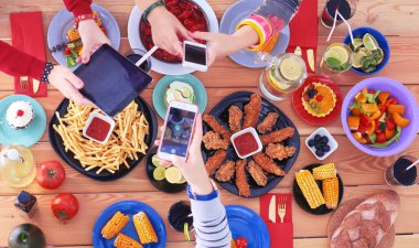Ahşap masada otururken birlikte yemek yiyen bir grup insanın üst düzey görüntüsü. Masada yemek var. İnsanlar fast food yiyor. Yemek fotoğrafı.