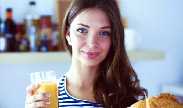 Junge Frau mit Glas Saft und Kuchen steht in Küche . — Stockfoto