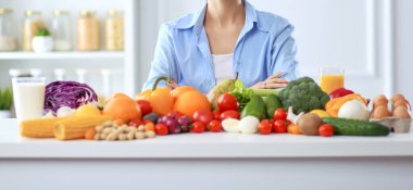 Ahşap iç kısımda meyve ve sebze dolu masada oturan genç ve tatlı bir kadın..