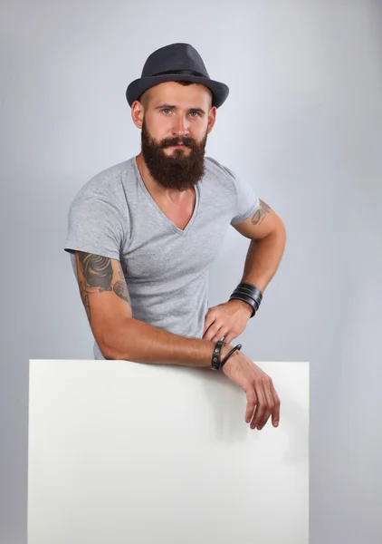 Portrét mladého muže v klobouku, stojící poblíž prázdné, izolované na w — Stock fotografie
