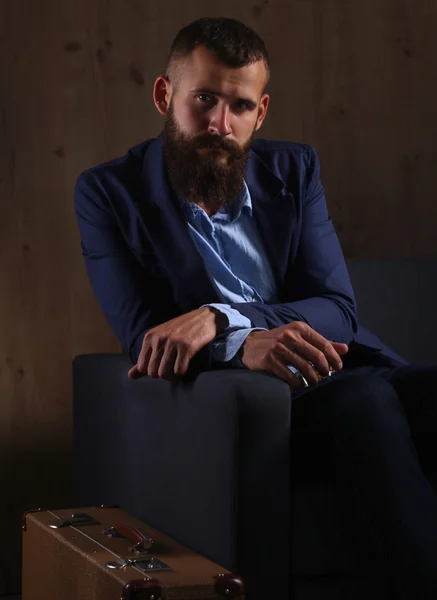 Businessman sitting the sofa in office lobby, isolated on dark — Stock Photo, Image