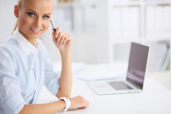 Atrakcyjna kobieta siedzi na biurku z laptopa w o — Zdjęcie stockowe