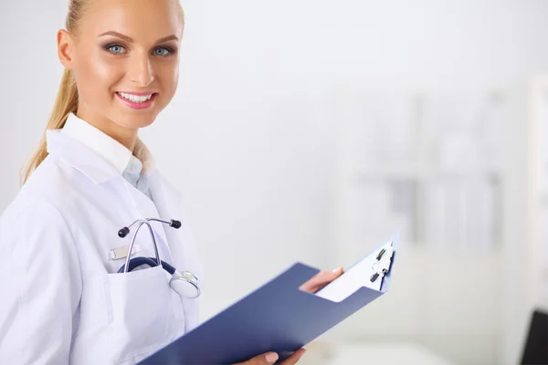 Médico sonriente con una carpeta en uniforme de pie en hosp —  Fotos de Stock