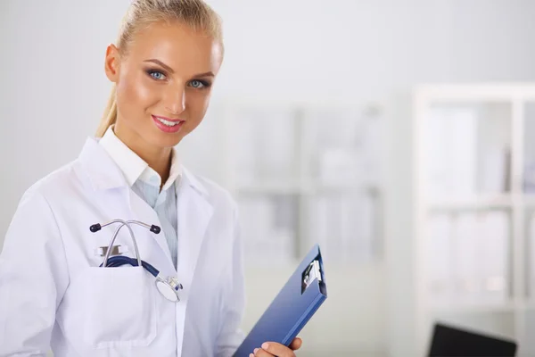 Femme médecin souriante avec un dossier en uniforme debout à hosp — Photo