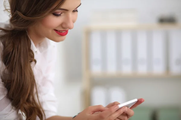 Empresária enviando mensagem com smartphone sentado no de — Fotografia de Stock