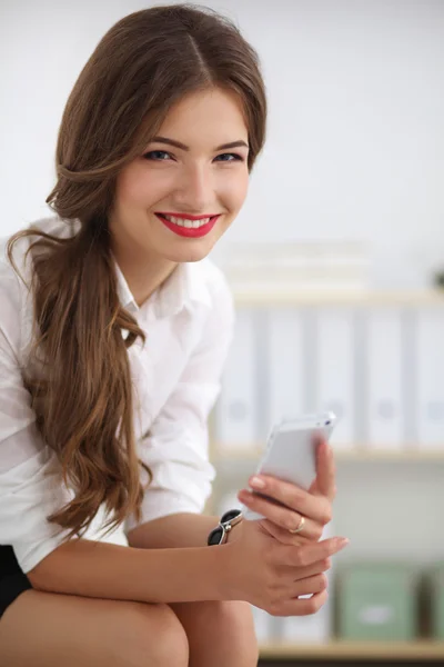 Empresaria enviando mensaje con teléfono inteligente sentado en el de — Foto de Stock