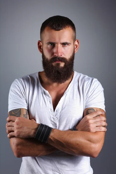 腕を組んだ立っているハンサムなひげを生やした男の肖像画です。 — ストック写真