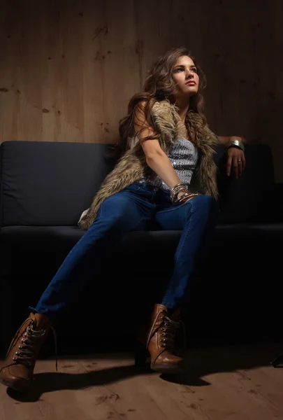 Portrait of elegant woman sitting on black sofa wearing a blue — Stock Photo, Image