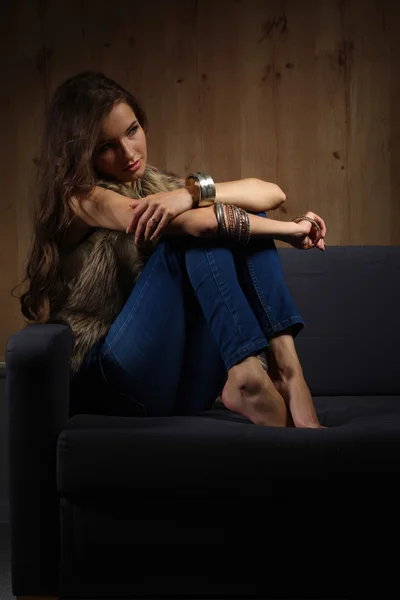 Portrait of elegant woman sitting on black sofa wearing a blue — Stock Photo, Image