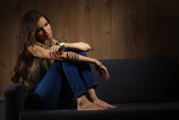 Porträt einer eleganten Frau, die auf einem schwarzen Sofa sitzt und ein blaues — Stockfoto