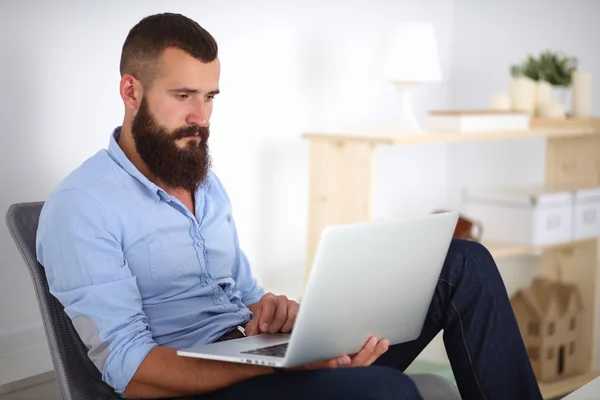 Snygg ung man sitter och arbetar på bärbar dator. — Stockfoto