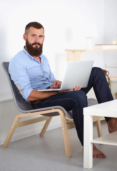 Knappe jongeman zitten en werken op laptop computer. — Stockfoto