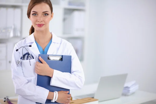 Femme médecin souriante avec un dossier en uniforme debout à hosp — Photo