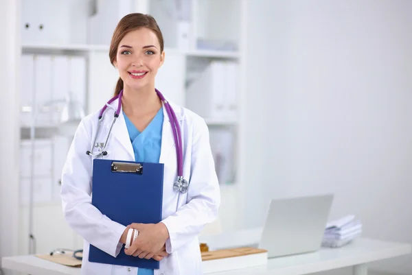 Smiling female doctor with a folder in uniform standing at hosp — Stock Photo, Image