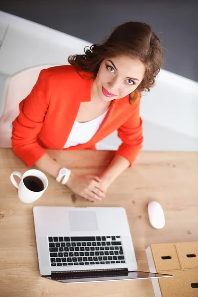 Atraktivní žena sedí za stolem v kanceláři a pracuje s notebookem — Stock fotografie