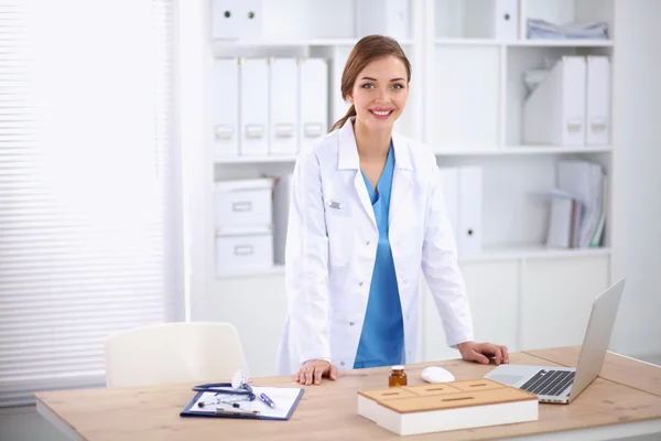 Unga läkare kvinna som står nära tabell på sjukhus — Stockfoto