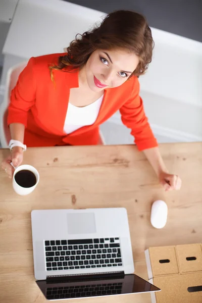 Mulher atraente sentada na mesa no escritório, trabalhando com laptop — Fotografia de Stock