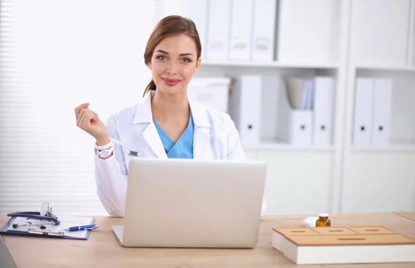 Female doctor sitting on the desk and working a laptop in hospi — Stock Photo, Image