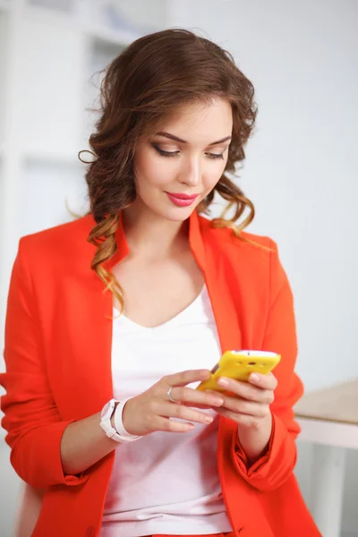 Bella donna d'affari utilizzando il telefono cellulare in piedi in ufficio — Foto Stock