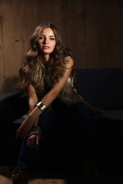 Retrato de una mujer elegante sentada en un sofá negro con un azul — Foto de Stock