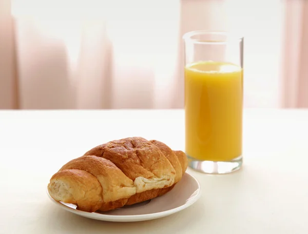 Croissanty, sklenice pomerančové šťávy a novin — Stock fotografie