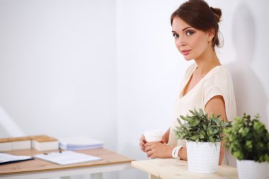 Ofiste masanın yanında duran çekici genç bir iş kadını.