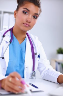 Kadın araştırmacı, beyaz arka planda izole edilmiş ilaç şişeleri ve mataralarla çevrili.