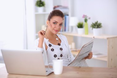 parlak ofis masasında oturup gazete tutan şirin iş kadını