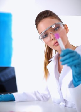 Kadın araştırmacı, beyaz arka planda izole edilmiş ilaç şişeleri ve mataralarla çevrili.