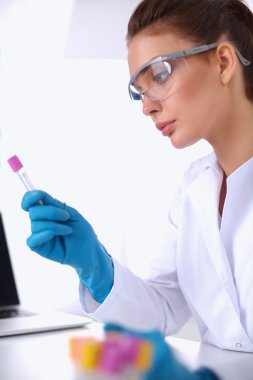 Kadın araştırmacı, beyaz arka planda izole edilmiş ilaç şişeleri ve mataralarla çevrili.