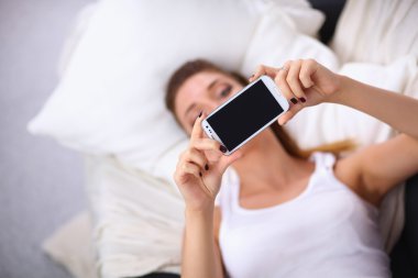 Yatak odasında cep telefonu ile kendini bir fotoğraf çekici mutlu esmer