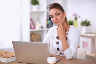 Masasında dizüstü bilgisayarla oturan bir iş kadınının portresi.