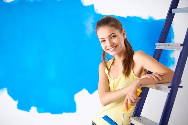 Feliz bela jovem fazendo pintura de parede, sentado na escada — Fotografia de Stock