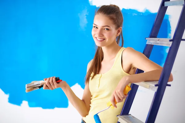 Feliz hermosa mujer joven haciendo pintura de pared, sentado en la escalera — Foto de Stock