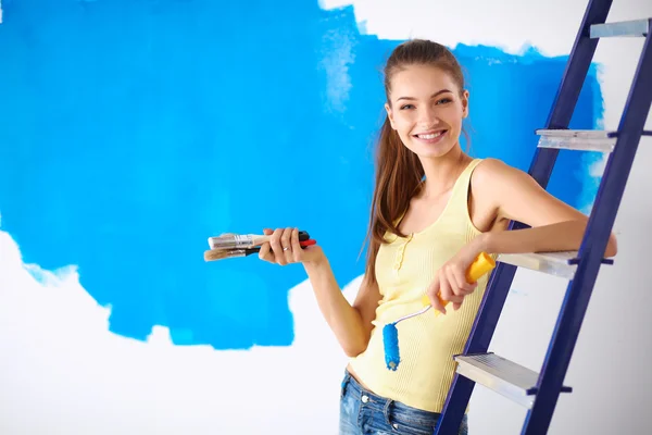 Joyeux belle jeune femme faisant de la peinture murale, assis sur l'échelle — Photo