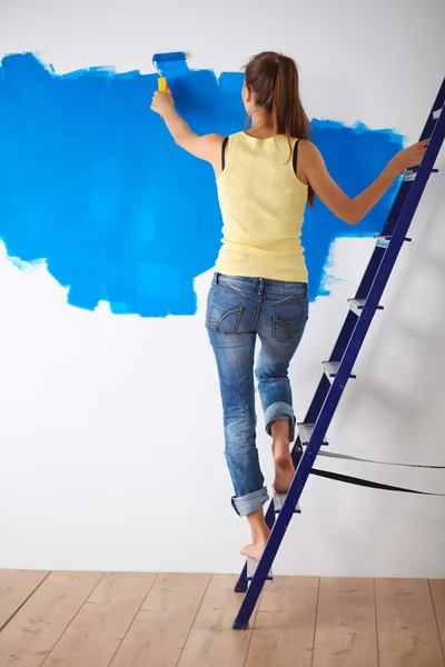 Felice bella giovane donna che fa pittura murale, in piedi sulla scala — Foto Stock