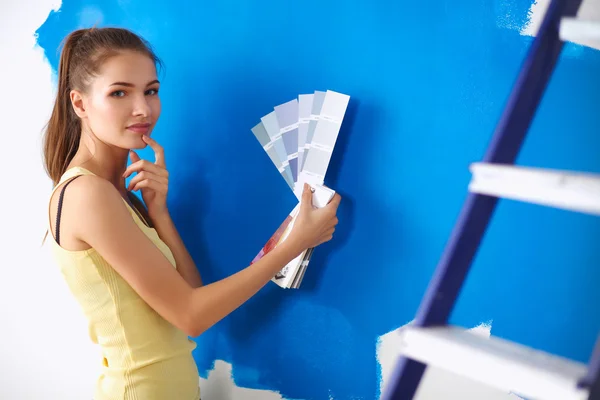 Mladá krásná žena drží paletu barev, stojí u zdi. — Stock fotografie