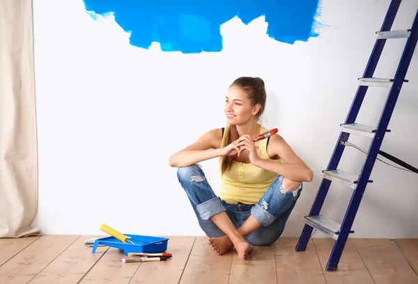 Portrait of female painter sitting on floor near wall after painting. — Stock Photo, Image