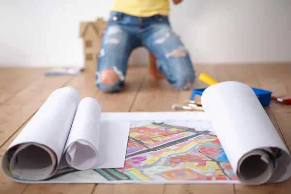 Jonge vrouw zittend op de vloer en kijken naar blauwdruk van nieuwe huis — Stockfoto