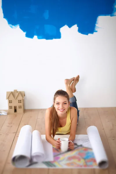 Ung kvinna liggande på golvet och tittar på blåkopia av nya hus — Stockfoto