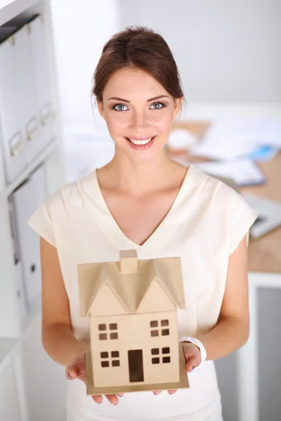 Retrato de una arquitecta sosteniendo una casita, de pie en la oficina, aislada —  Fotos de Stock