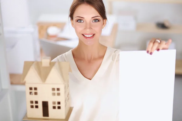 Portrait of female architect holding a little house, standing in office, isolated — Stock Photo, Image