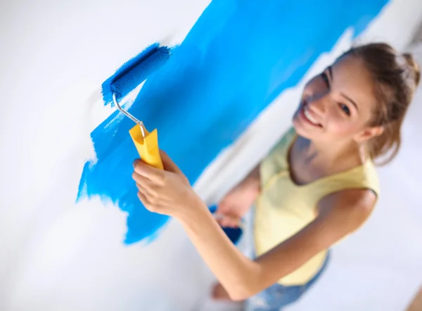 Happy beautiful young woman doing wall painting, standing on ladder — Stock Photo, Image