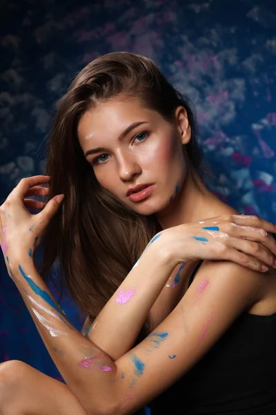 Young woman sitting near painting wall — Stock Photo, Image