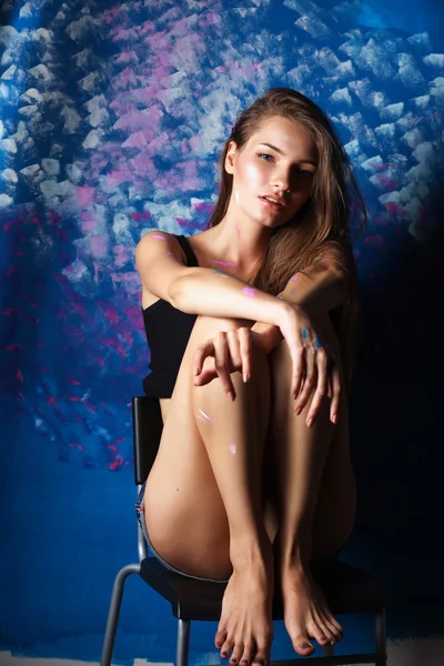 Young woman sitting near painting wall — Stock Photo, Image