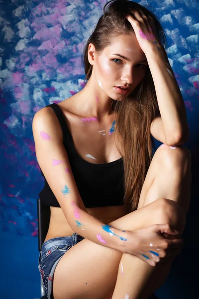 Young woman sitting near painting wall — Stock Photo, Image