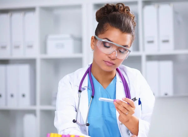 Woman researcher is surrounded by medical vials and flasks, isolated on white background — Stock Photo, Image