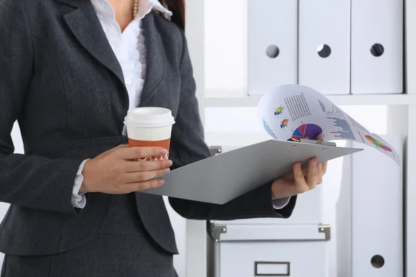 Femme d'affaires avec des dossiers et une tasse de café, debout dans le bureau — Photo