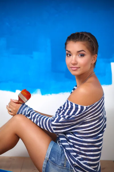 Portrait of female painter sitting on floor near wall after painting. — Stock Photo, Image