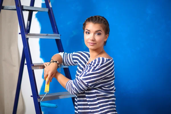 Joyeux belle jeune femme faisant de la peinture murale, debout sur l'échelle — Photo